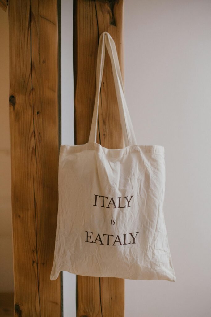 A recycled canvas tote bag with soft beige fabric and subtle printed text. Custom merchandise product.